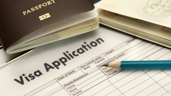 Ein englisches Visum-Antragsformular mit einem Reisepass und Stift zur Vorbereitung wichtiger Visa- und Aufenthaltsunterlagen für den Auslandsumzug mit DACHSER & KOLB.