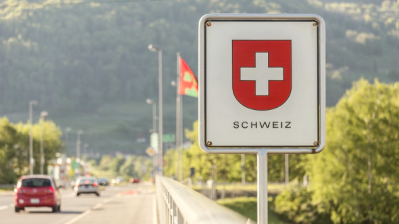 Ein offizielles Hinweisschild mit dem Schweizer Wappen an einem Grenzübergang für die Zollabwicklung beim Umzug in die Schweiz mit DACHSER & KOLB.