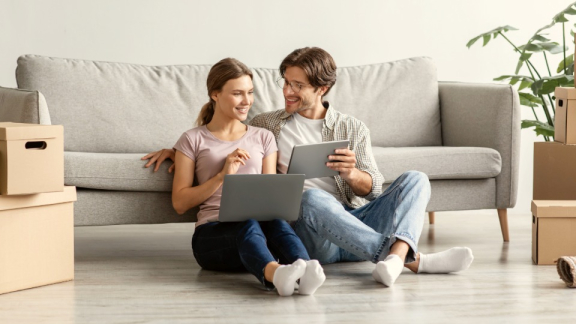 Ein Paar berechnet glücklich am Laptop und Tablet die Kosten für den Australien-Umzug im Online-Umzugskostenrechner von DACHSER & KOLB.