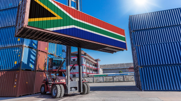 Ein Containerstapler hebt einen Überseecontainer mit der Nationalflagge von Südafrika für die Zollabwicklung mit DACHSER & KOLB.