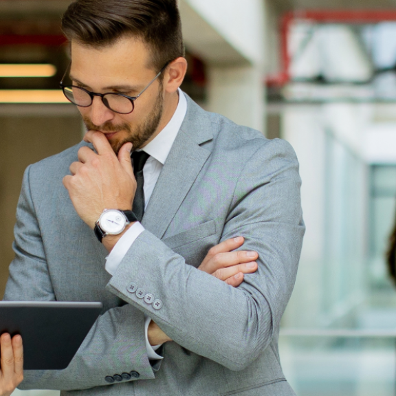 Zwei professionelle Personen besprechen Karrierepläne auf einem Tablet in einem modernen Büro.