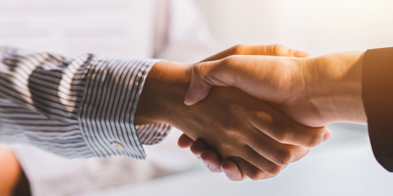 Händeschütteln zweier Personen bei einem Geschäftstreffen oder Jobangebot. Symbol für Einigung und berufliche Chance.