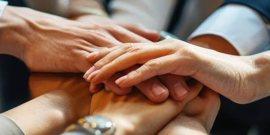 Mehrere Hände übereinander als Symbol für positive Unternehmenskultur und Teamzusammenarbeit.
