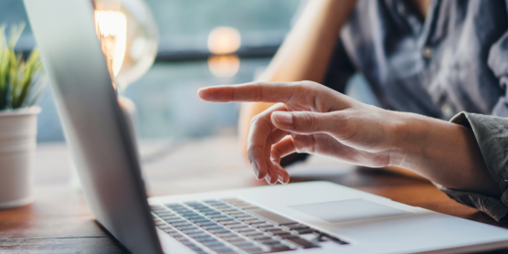 Hände zeigen auf einen Laptop während einer Diskussion zu Karriere-FAQs an einem Holztisch.