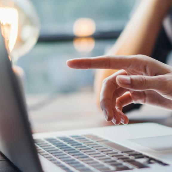 Hände zeigen auf einen Laptop während einer Diskussion zu Karriere-FAQs an einem Holztisch.