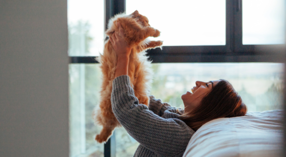 Frau hebt ihre Katze nach dem Umzug hoch – emotionale Bindung stärken beim Umzug mit Katzen