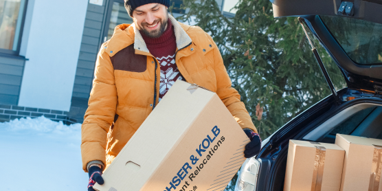 Vater und Kind beim Umzug im Winter – Umzugskartons werden bei Schnee ins neue Zuhause getragen