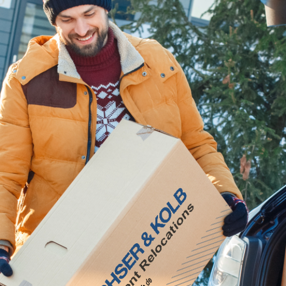 Vater und Kind beim Umzug im Winter – Umzugskartons werden bei Schnee ins neue Zuhause getragen