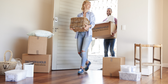 Paar trägt Umzugskartons und Körbe in neues Zuhause – Tipps und Hilfe im Umzugsratgeber