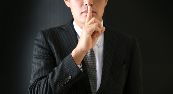 Diskretion bei einem VIP-Umzug für prominente Persönlichkeiten – ein Mann signalisiert Vertraulichkeit mit Finger auf Lippen