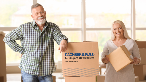 Seniorenpaar beim Umzug in gehobene Wohnresidenz mit DACHSER & KOLB – Umzugskartons in heller, freundlicher Wohnung