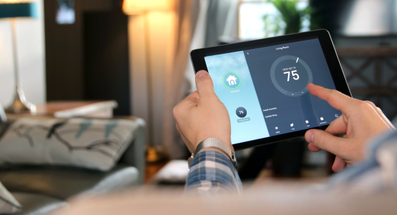 Smart-Home-Technologien: Person regelt Raumtemperatur bequem per Tablet für barrierefreies und komfortables Wohnen