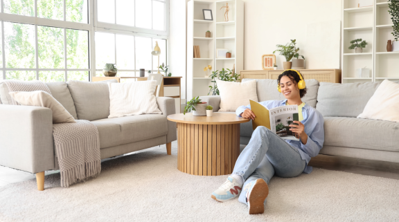 Frau mit Kopfhörern liest entspannt Zeitschrift im neuen Wohnzimmer. Entspannungstechniken für den Umzug, Ruhe finden.