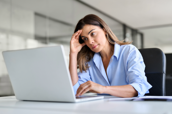 Nachdenkliche Frau vor Laptop – symbolisiert emotionalen Stress beim Übergang in einen neuen Lebensabschnitt.