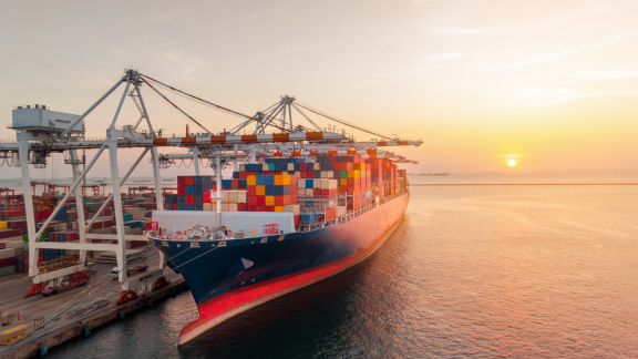 Containerschiff bei Sonnenuntergang im Hafen – Symbolbild für Planung zur Vermeidung von Havarien im Seetransport