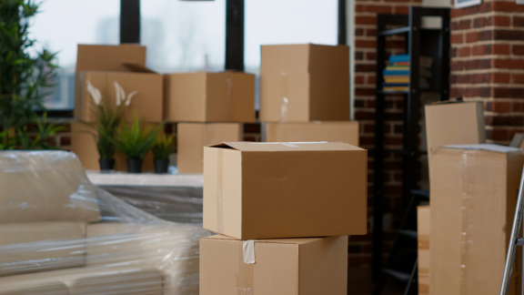 Mehrere braune Umzugskartons unterschiedlicher Größen in einem Raum mit Umzugsgut.