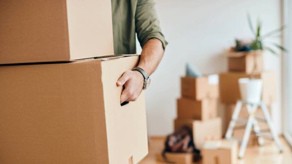 Person trägt Umzugskartons – Transport als möglicher Anlass für Schadensbearbeitung
