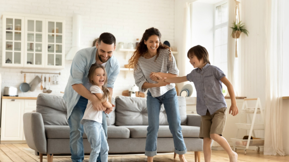 Glückliche Familie spielt in ihrem neuen, hellen Zuhause. Symbolisiert den gelungenen Umzug mit Relocation Service für Privatpersonen.