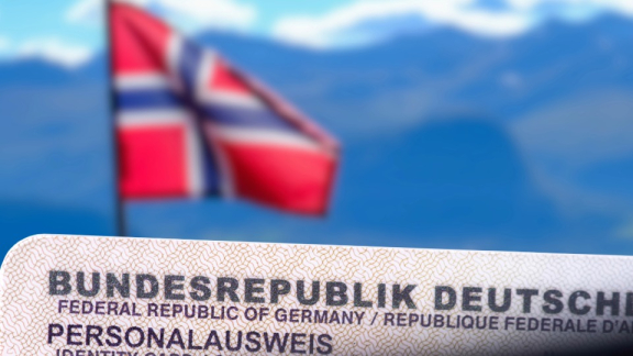Deutscher Personalausweis im Vordergrund, unscharfe norwegische Flagge und Berge im Hintergrund