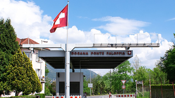 Schweizer Grenzübergang mit Zollstation und Schweizer Flagge bei Tageslicht