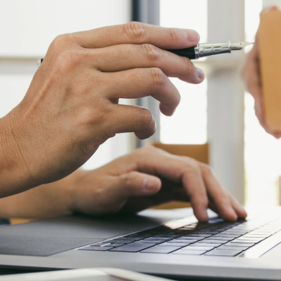 Eine Koordination am Laptop neben einem Umzugskarton und Paketband für die strategische Beschaffung von Moving- und Relocation-Leistungen im B2B-Procurement.
