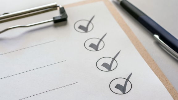 Eine strukturierte Checkliste mit gesetzten Haken auf einem Klemmbrett neben einem Kugelschreiber für eine transparente Projektabwicklung durch DACHSER & KOLB.