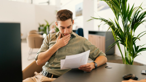 Ein Mitarbeiter analysiert konzentriert Dokumente am Schreibtisch im modernen Büro – Strukturierung komplexer Anforderungen und zeitkritischer Abläufe in der Logistik.