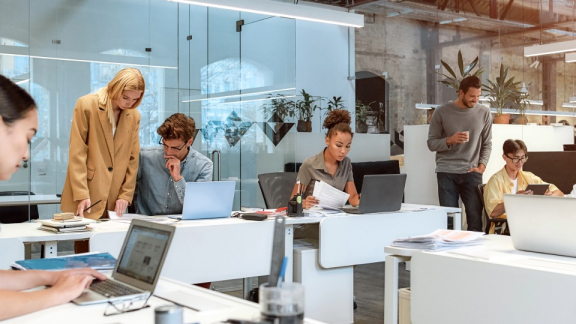 Mitarbeiter in einem modernen Co-Working-Space arbeiten flexibel an Laptops.