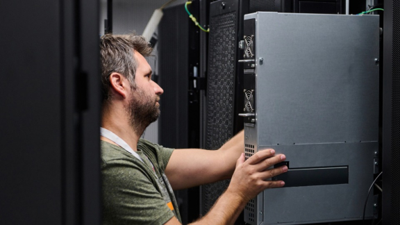 IT-Umzug mit DACHSER und KOLB – Ein IT-Logistiker schiebt ein Server-Rack-Gehäuse im Rechenzentrum ein.