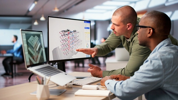 Zwei Projektplaner analysieren die digitale Infrastruktur-Planung am Bildschirm für die strukturierte Standortverlagerung mit DACHSER & KOLB.