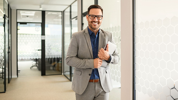 Ein lächelnder B2B-Projektmanager im modernen Büro als persönlicher Ansprechpartner für den Firmenumzug mit DACHSER & KOLB.