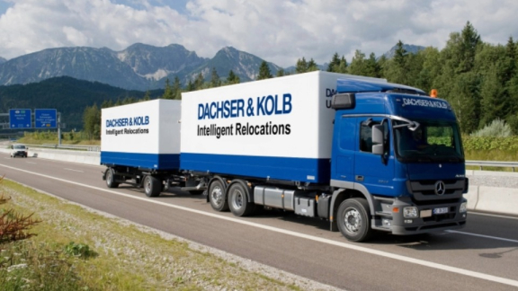 Ein blauer Umzugs-LKW von DACHSER & KOLB mit Anhänger auf der Autobahn zur Sicherung von Transportkapazitäten im bundesweiten Netzwerk.