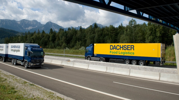 Ein Umzugs-LKW von DACHSER & KOLB und ein LKW der DACHSER Food Logistics auf der Autobahn vor einer Bergkulisse zur Veranschaulichung der Netzwerkkraft.