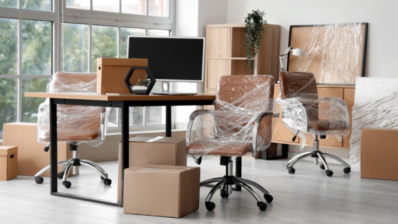Eingewickelte Bürostühle und gepackte Umzugskartons während einer professionellen Standortverlagerung und Inhouse-Logistik mit DACHSER & KOLB.